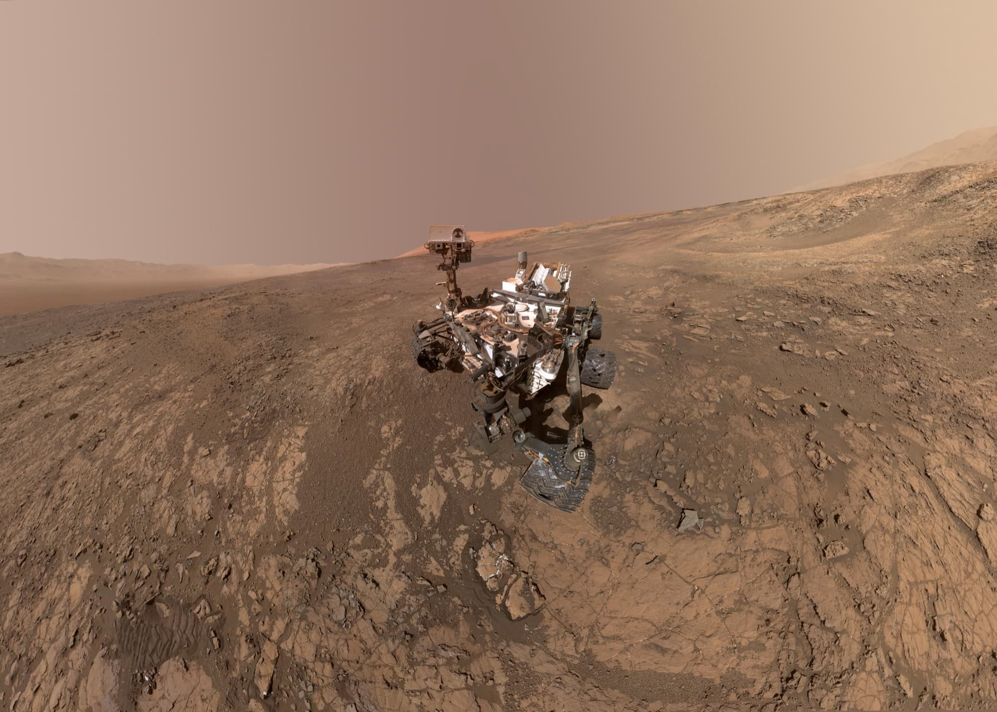 PIA22207, a self-portrait of Curiosity standing on Vera Rubin Ridge, assembled from dozens of Mars Hand Lens Imager frames all taken on 23 January 2018, sol 1943, with the lower slopes of Aeolis Mons rising just behind the rover's mast and the rim of Gale crater on the horizon at both edges.
