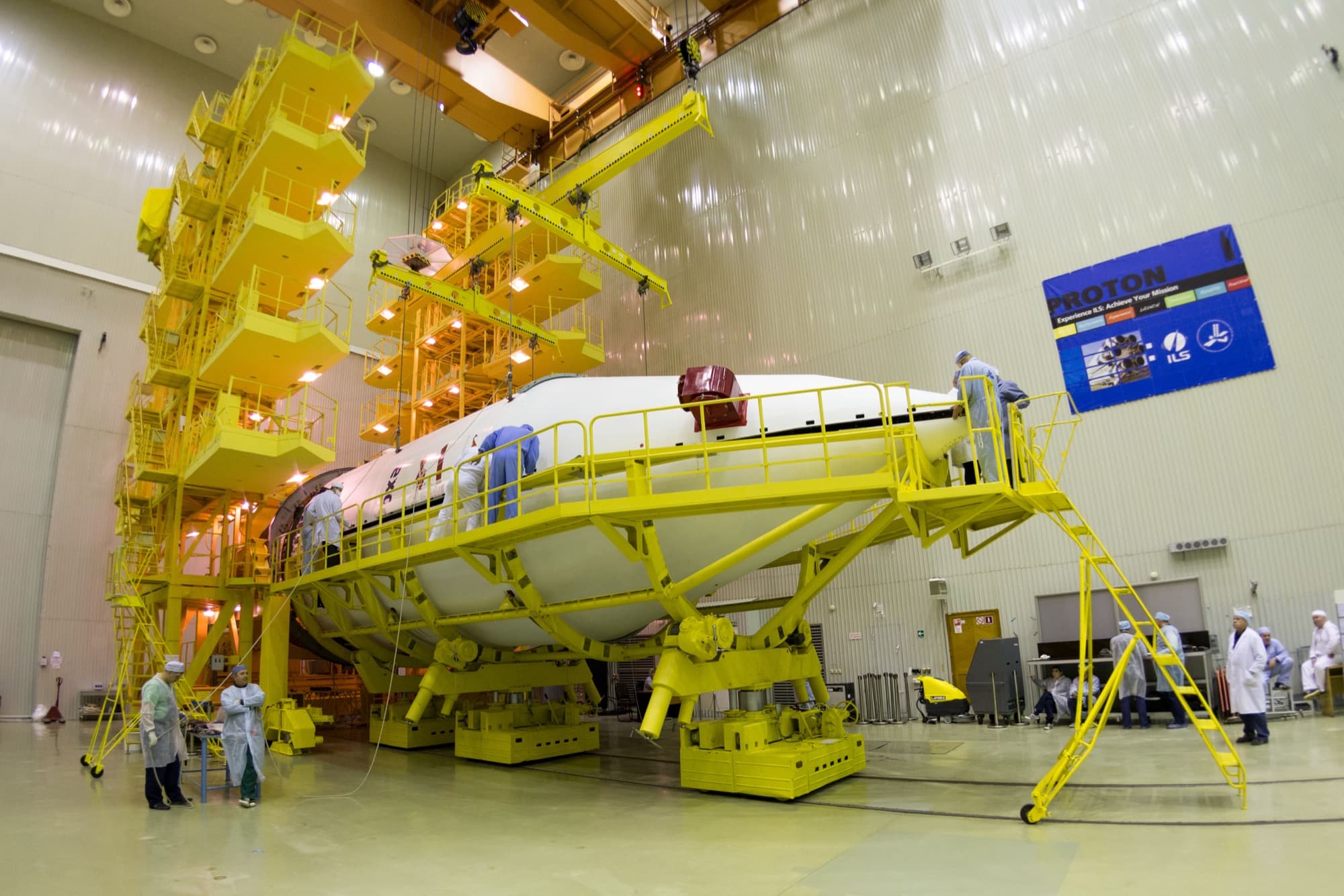 The assembled ExoMars 2016 spacecraft composite, the Trace Gas Orbiter with the Schiaparelli demonstrator mounted on it, photographed on 2 March 2016 at the Baikonur cosmodrome as the second half of the Proton launcher fairing is lowered around it by overhead crane.