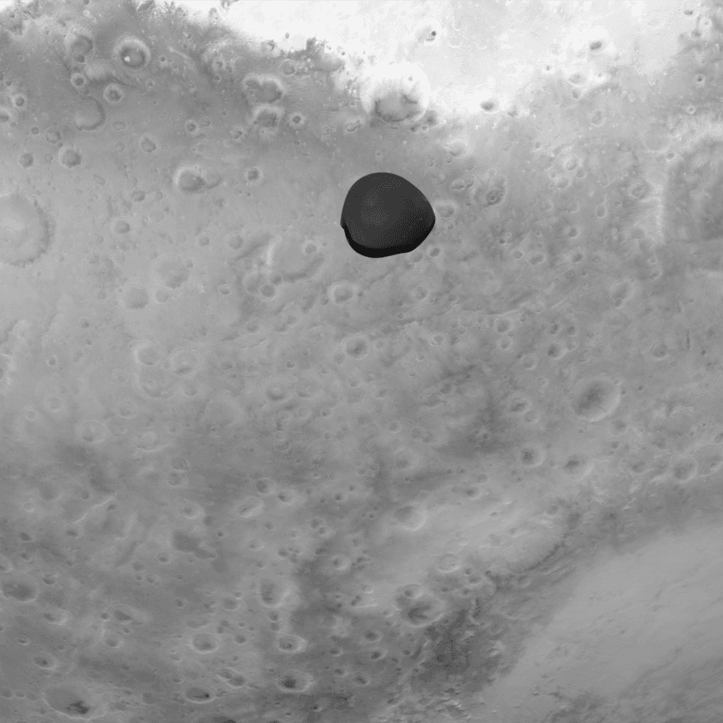 Deimos as a dark, irregular silhouette against the brighter disc of Mars, in a monochrome visible-light frame from Hera's 1020 by 1020 pixel Asteroid Framing Camera taken during the gravity assist of 12 March 2025 from about 1,000 km. ESA's caption places the bright Terra Sabaea region at the top, part of the 450 km Huygens crater at the right and part of Hellas Basin at the bottom right.