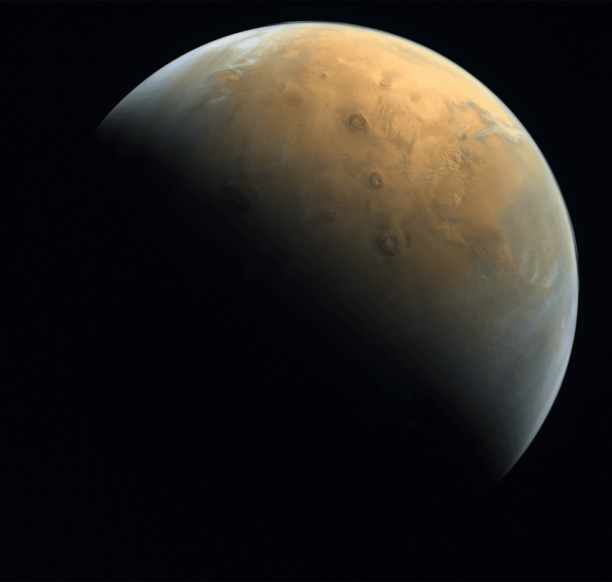 Hope's first science image of Mars, taken by the Emirates eXploration Imager on 10 February 2021 from about 24,700 km altitude, one day after orbit insertion, showing the north polar region and Olympus Mons catching the sunrise.