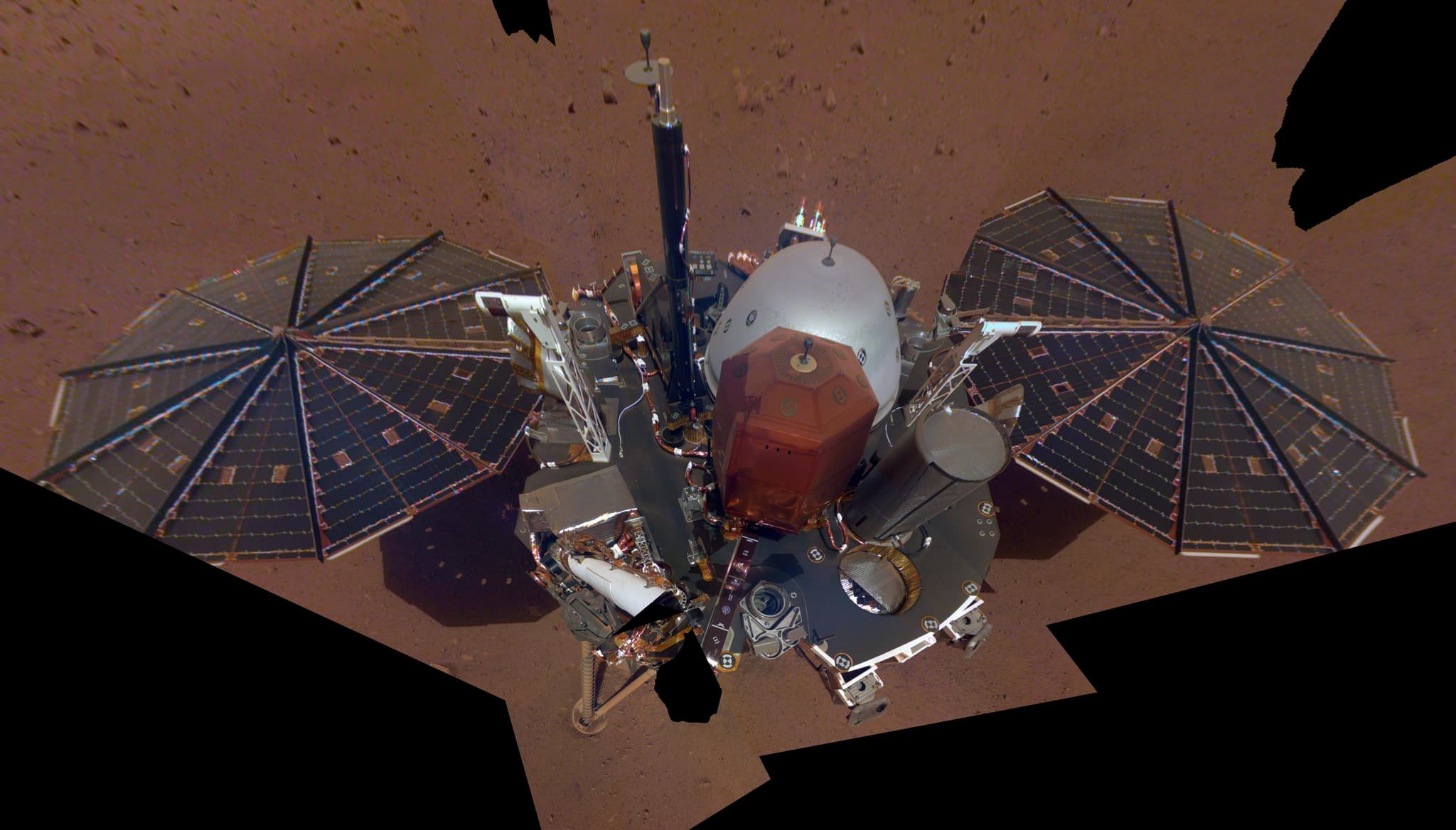 InSight's first full selfie, a mosaic of 11 frames taken by the Instrument Deployment Camera on the elbow of the robotic arm on 6 December 2018, showing the solar panels, the deck, the weather sensor booms and the UHF antenna.