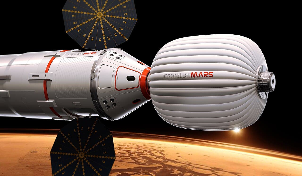 The foundation's own early artist's conception of the Inspiration Mars vehicle: a crew capsule on a cylindrical service module with two dark solar arrays, docked nose to nose with a ribbed white inflatable habitat lettered InspirationMARS, coasting above the orange limb of the planet.
