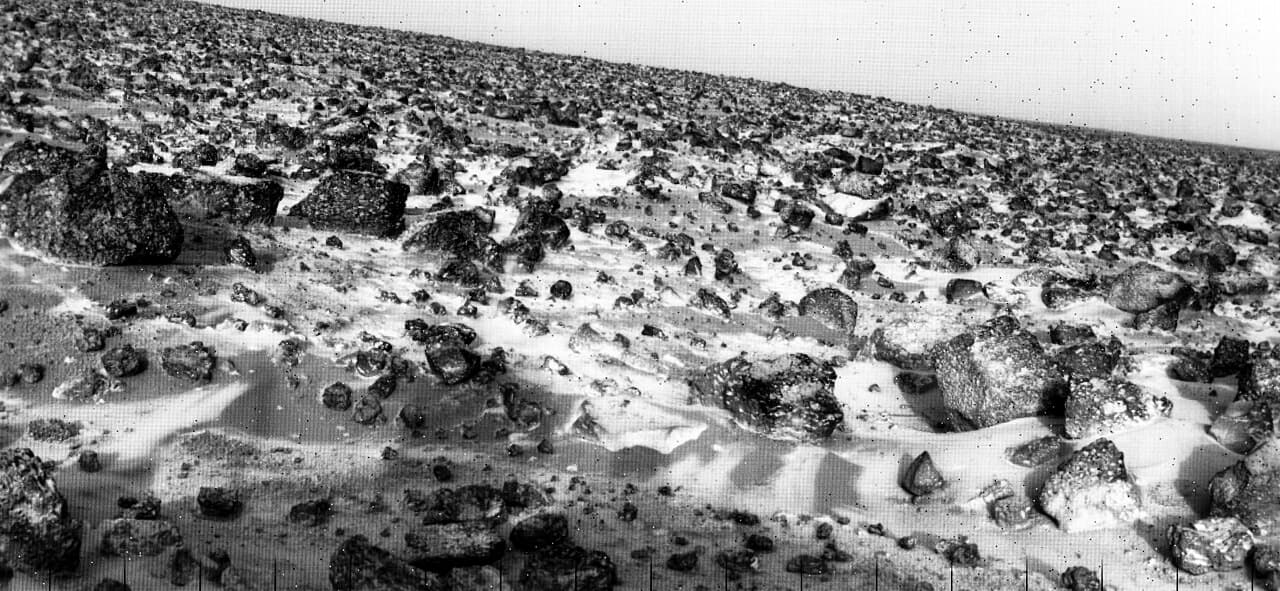 Frost banked around rocks and lying in patches across the soil at the Viking 2 site in Utopia Planitia, photographed on 18 May 1979 and relayed to Earth by Viking Orbiter 1 on 7 June 1979. NASA described it as a thin coating of water ice on the rocks and soil.