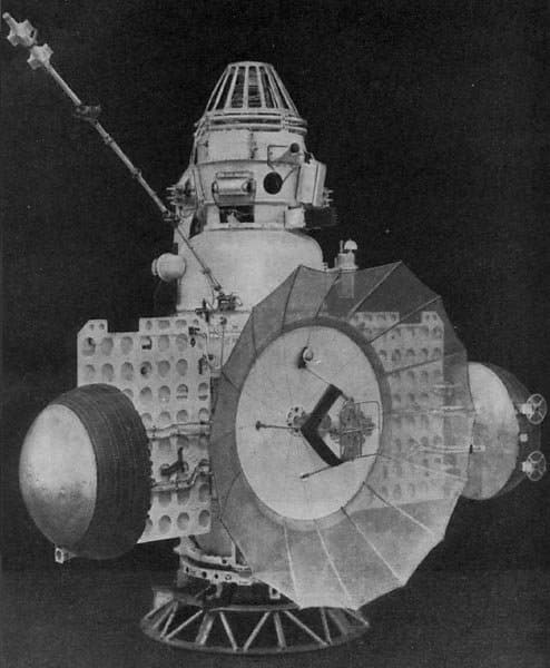A black and white photograph of a 3MV spacecraft on its handling ring against a dark backdrop, showing the ribbed umbrella high gain antenna, the two thermal radiator hemispheres, the perforated panel structure, the magnetometer boom and the latticed descent cone on top. NASA released it captioned as Zond 2; the same photograph appears on mentallandscape.com captioned as Zond 3, and the two vehicles were near identical 3MV craft.