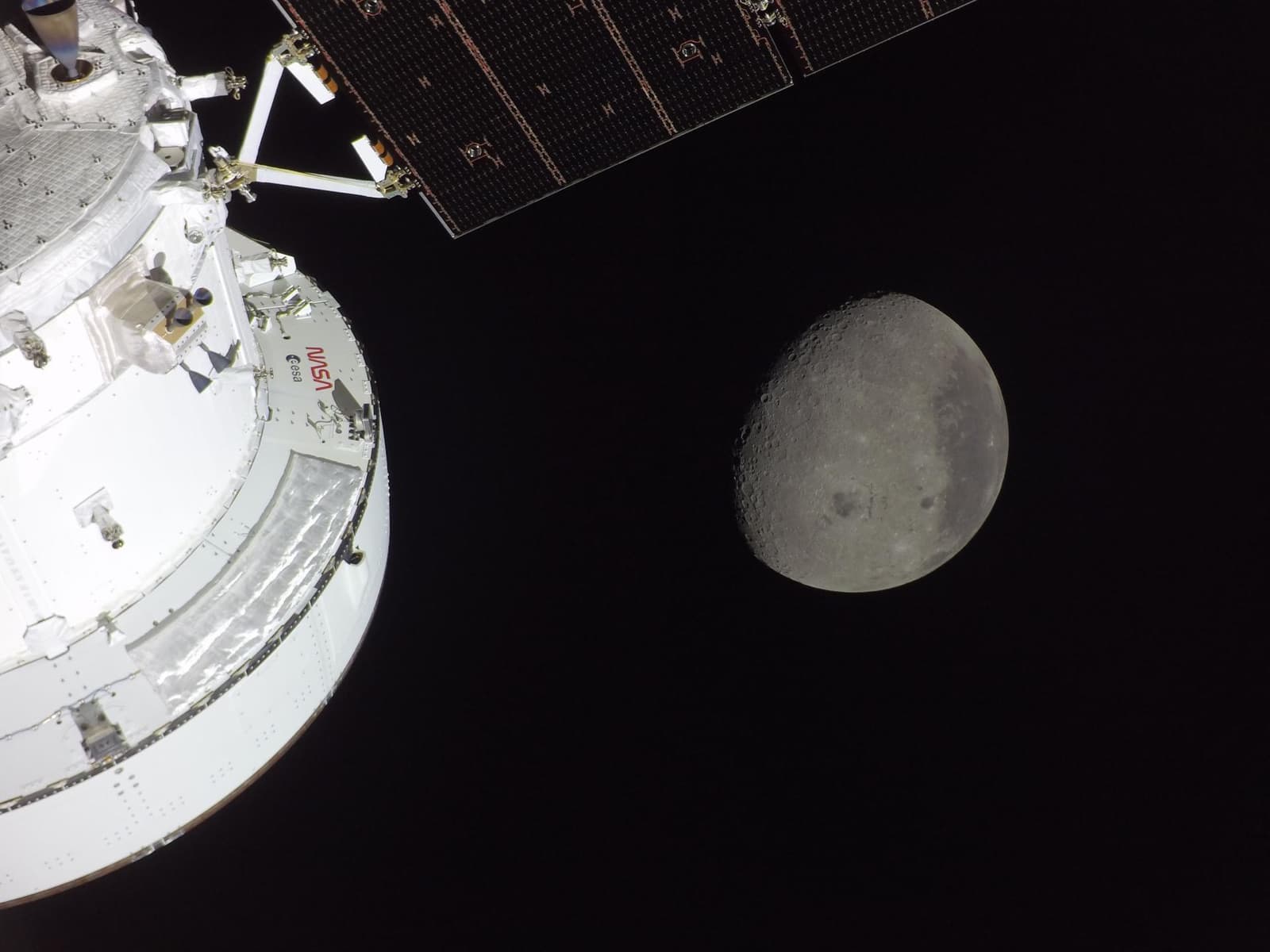Photograph: part of the Artemis II Orion spacecraft, lit by the Sun, with a waxing gibbous Moon beyond on 6 April 2026, the day of the crew's lunar flyby